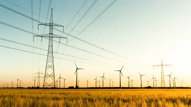 Transmission towers with wind turbines in the distance.